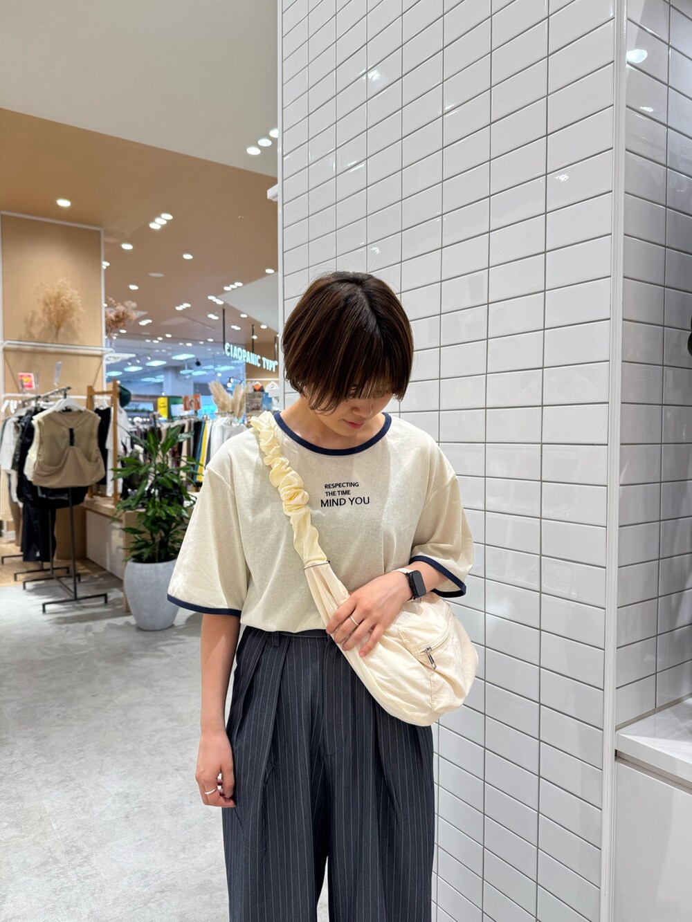 グレー系のスラックス、ホワイト系のトートバッグ、ホワイト系のTシャツ/カットソーを着用したレディースの夏コーディネートの4枚目の写真