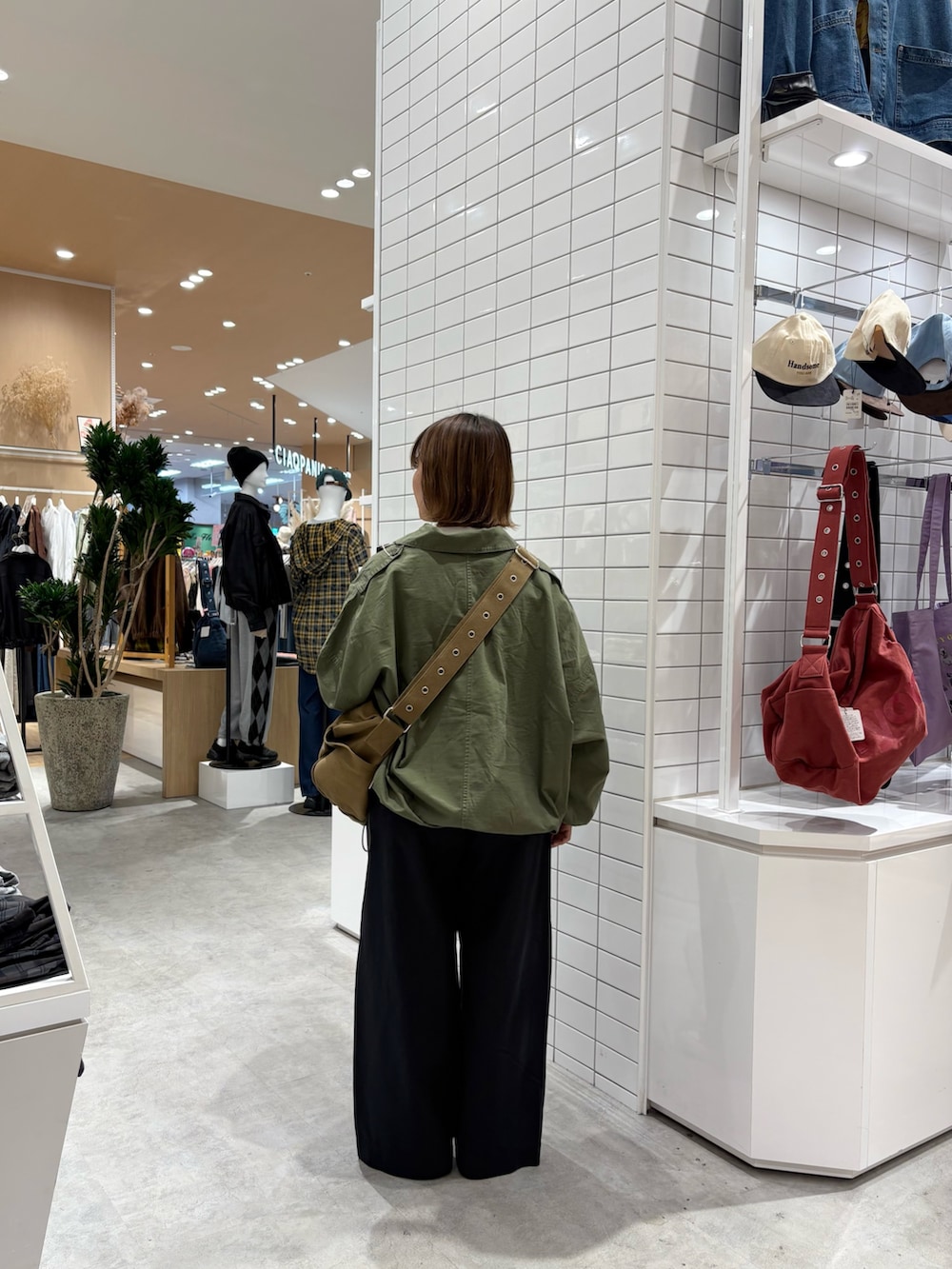 ブラック系のデニムパンツ、グリーン系のブルゾン、ブラウン系のトートバッグを着用したレディースの秋コーディネートの3枚目の写真