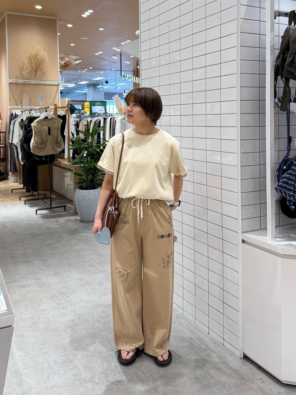 ホワイト系のTシャツ/カットソー、ベージュ系のサロペット/オーバーオール、ブラウン系のトートバッグを着用したレディースの夏コーディネートの3枚目の写真
