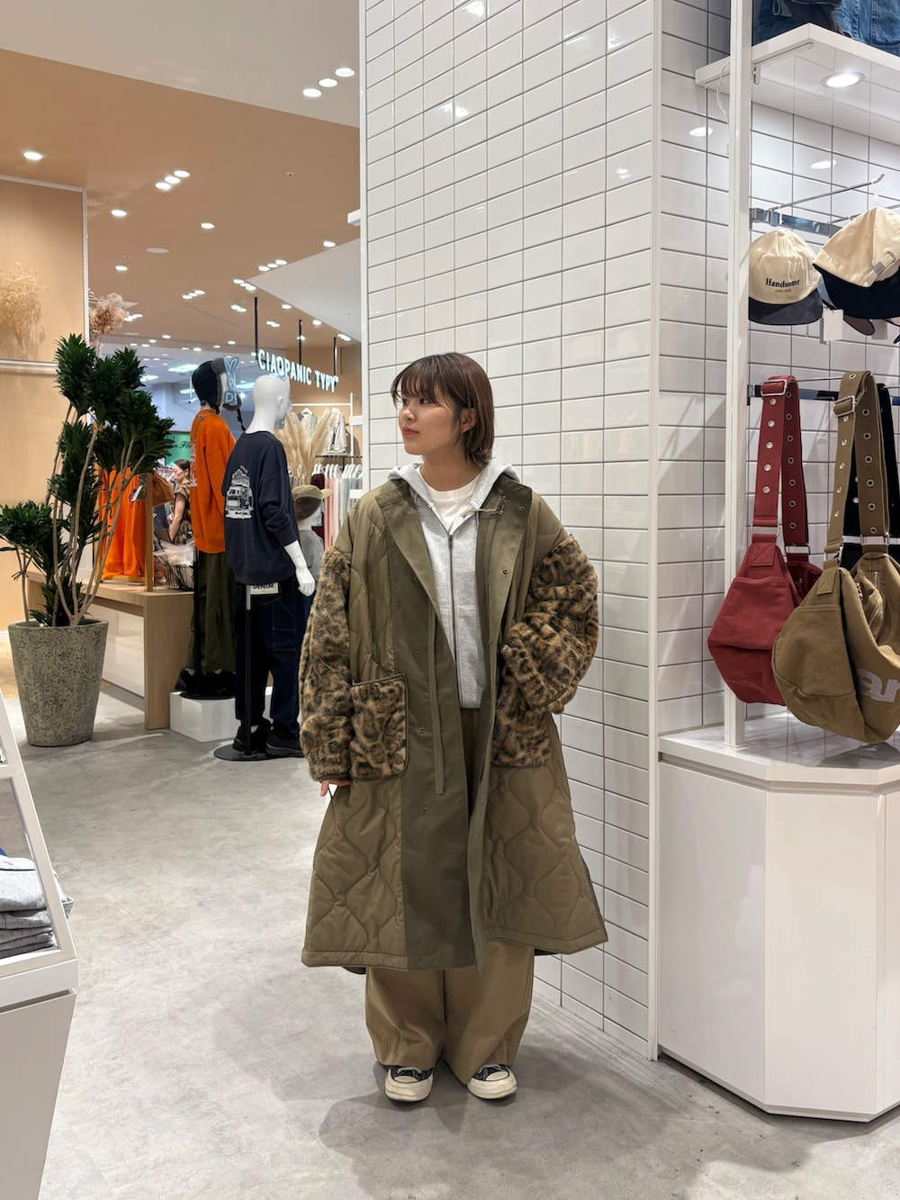 グレー系のパーカー、ベージュ系のデニムパンツ、グリーン系のノーカラーコートを着用したレディースの秋コーディネートの3枚目の写真