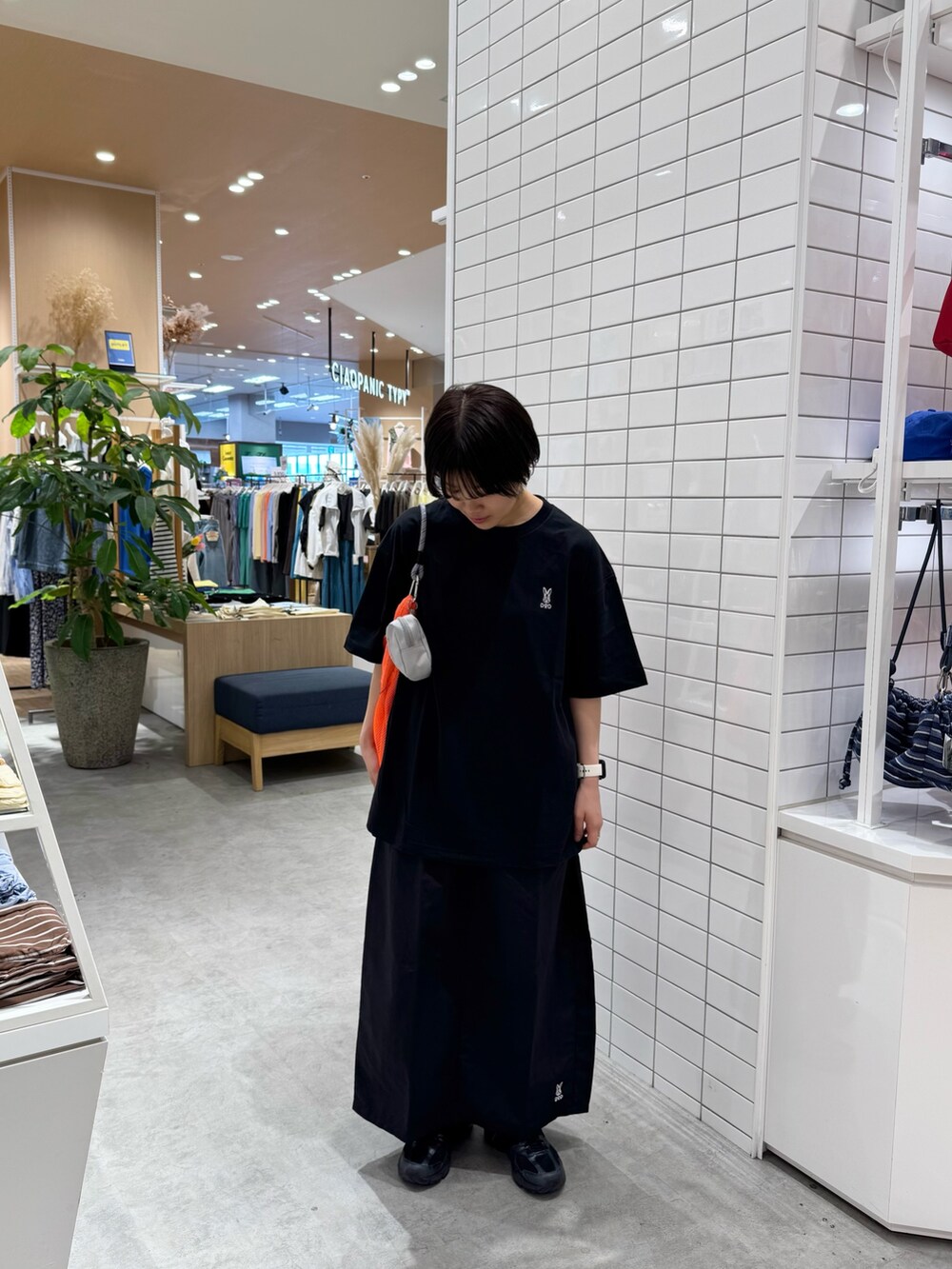 ブラック系のTシャツ/カットソー、ブラック系のスカート、オレンジ系のトートバッグを着用したレディースの春コーディネートの4枚目の写真