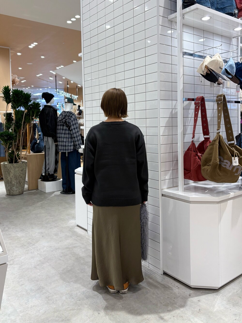 グレー系のニット/セーター、グリーン系のスカート、グレー系のトートバッグを着用したレディースの秋コーディネートの4枚目の写真