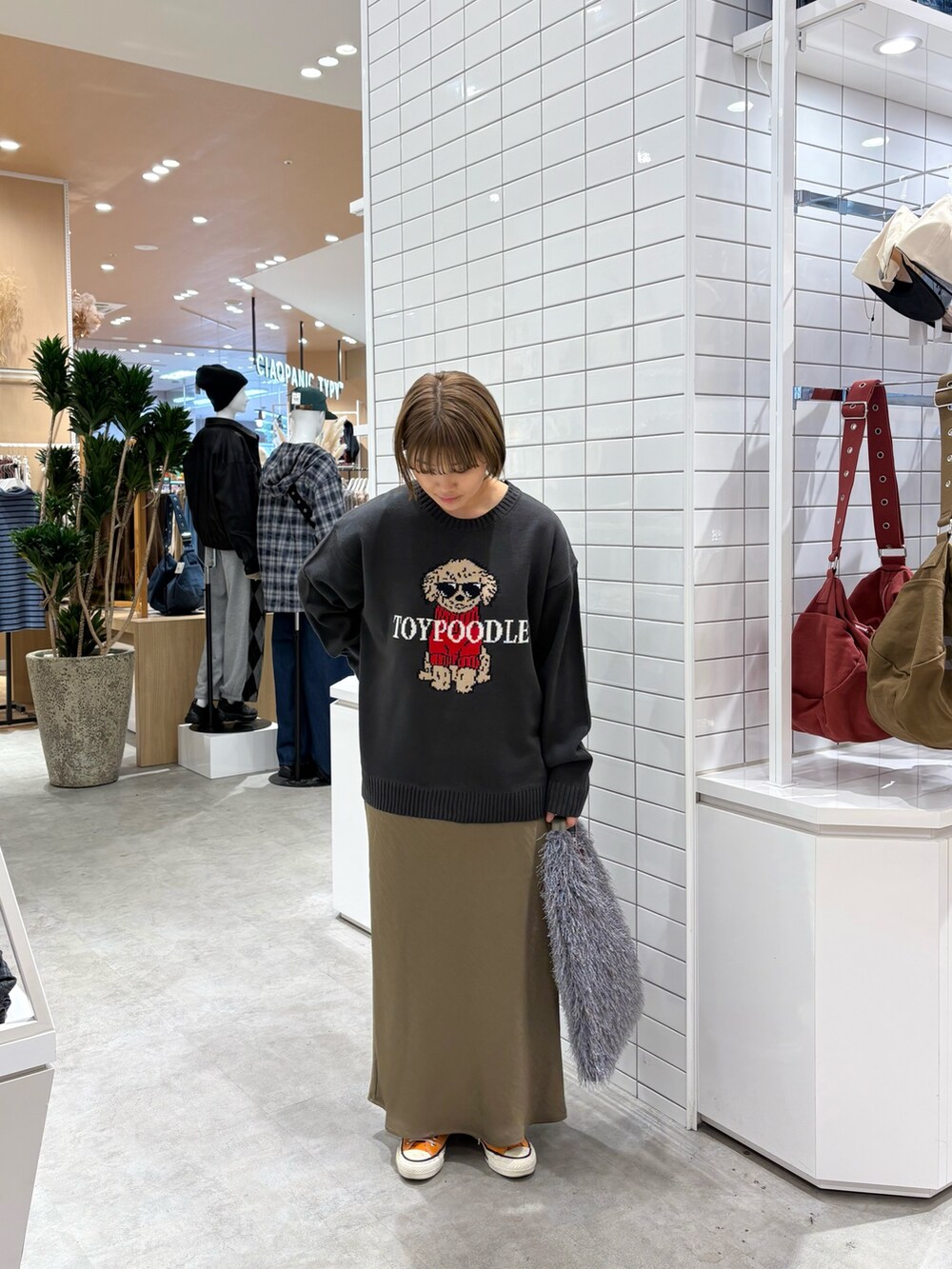 グレー系のニット/セーター、グリーン系のスカート、グレー系のトートバッグを着用したレディースの秋コーディネートの2枚目の写真