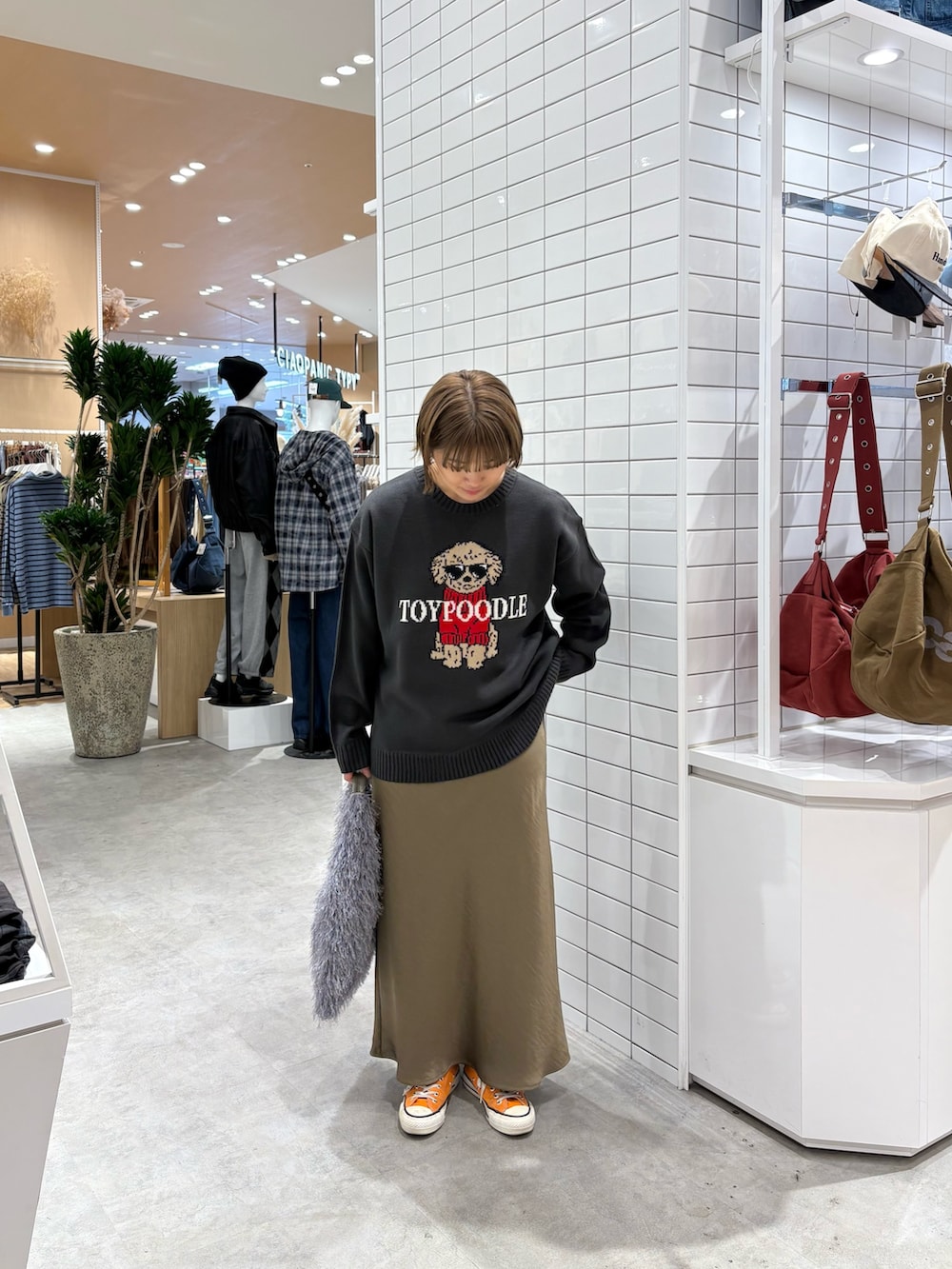 グレー系のニット/セーター、グリーン系のスカート、グレー系のトートバッグを着用したレディースの秋コーディネートの3枚目の写真