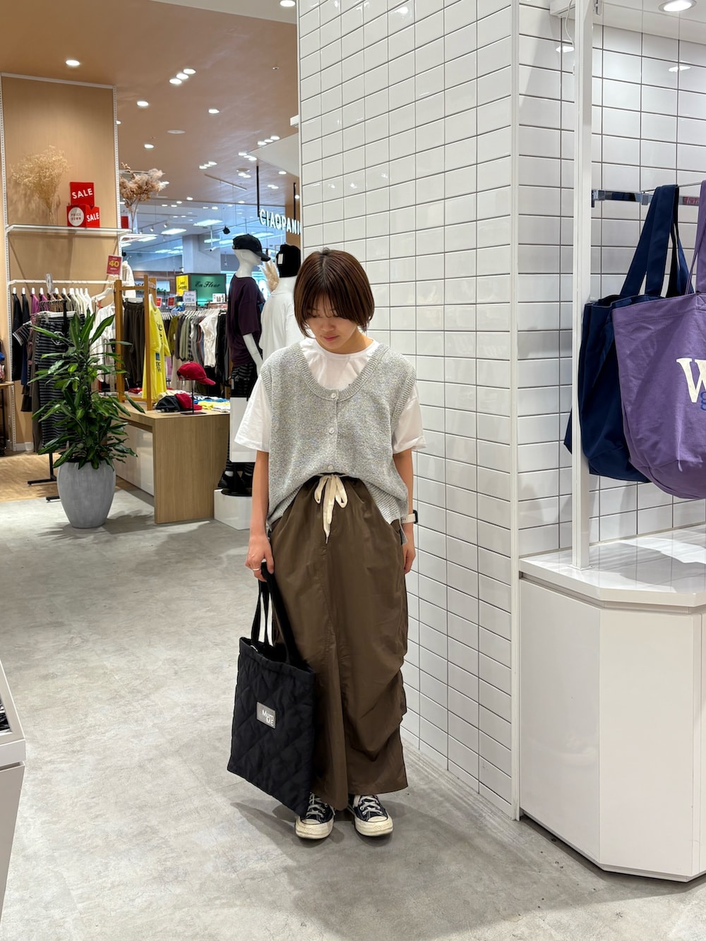 ブラウン系のスカート、ホワイト系のベスト、ホワイト系のTシャツ/カットソーを着用したレディースの秋コーディネートの2枚目の写真