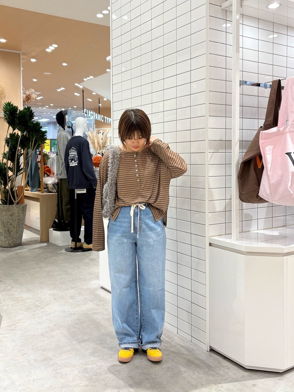 ブラウン系のTシャツ/カットソー、ブルー系のデニムパンツ、グレー系のトートバッグを着用したレディースの秋コーディネートの3枚目の写真