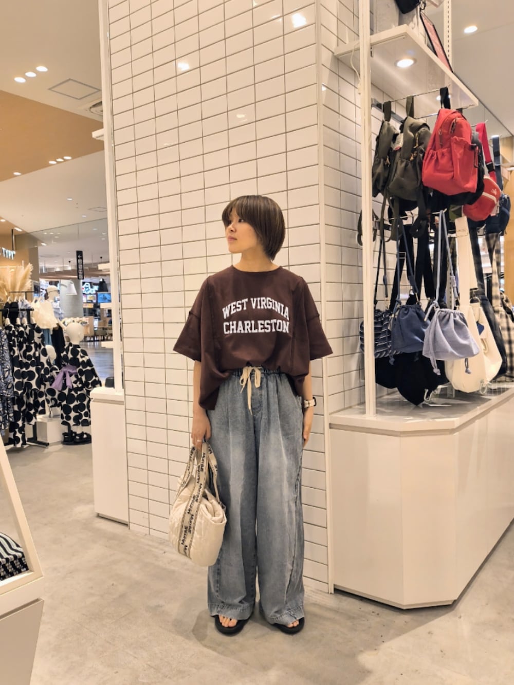 ブルー系のデニムパンツ、ホワイト系のトートバッグ、ブラウン系のTシャツ/カットソーを着用したレディースの夏コーディネートの2枚目の写真