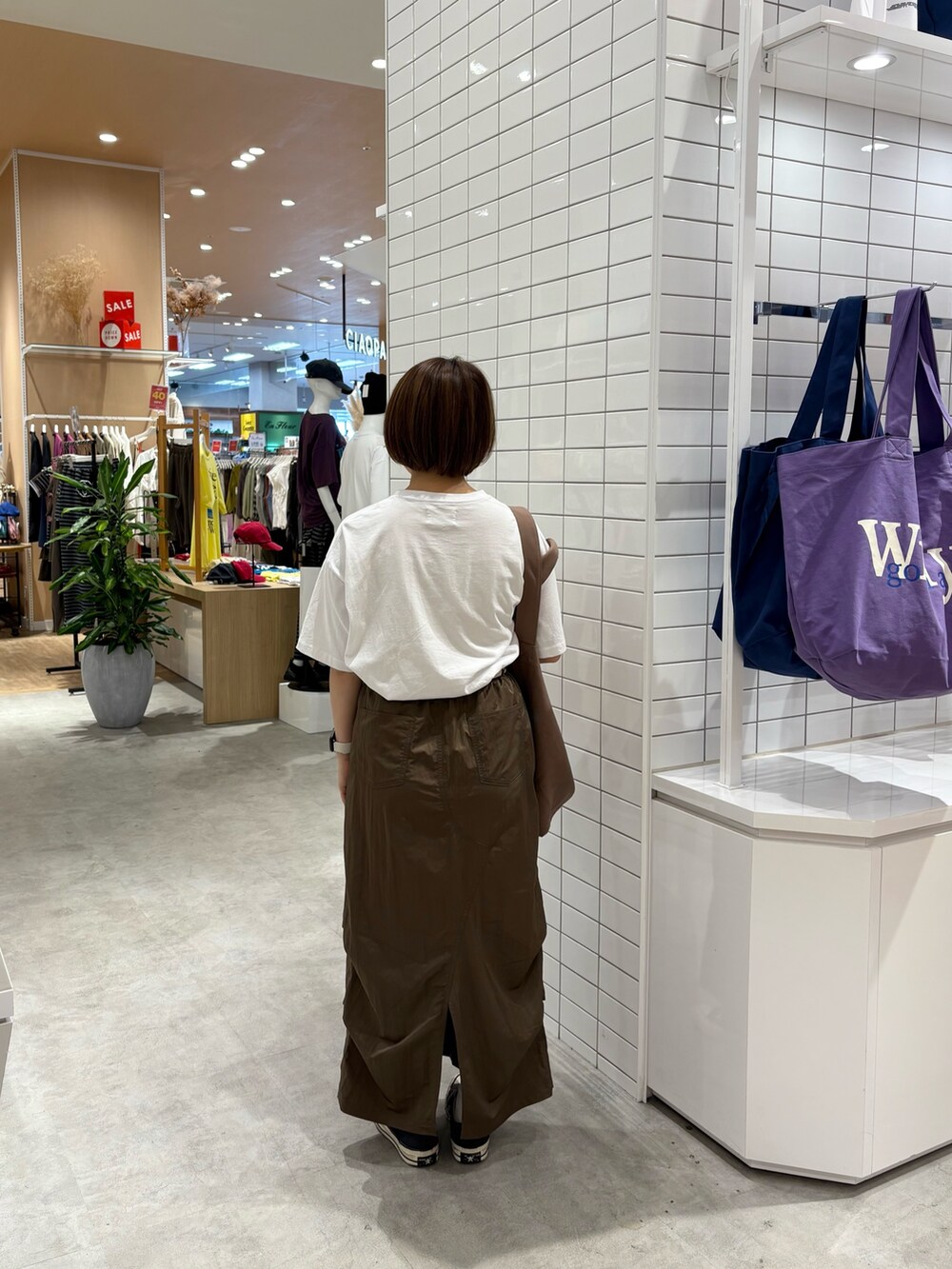 ホワイト系のTシャツ/カットソー、ブラウン系のスカート、ブラウン系のトートバッグを着用したレディースの秋コーディネートの4枚目の写真