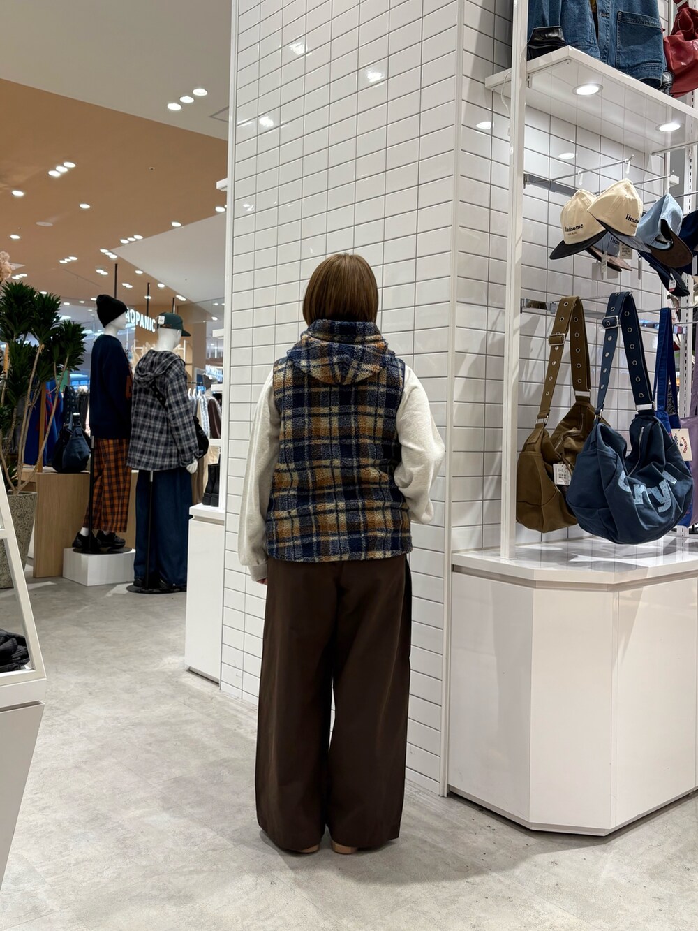 ブラウン系のデニムパンツ、ホワイト系のスウェット、オレンジ系のベストを着用したレディースの秋コーディネートの5枚目の写真