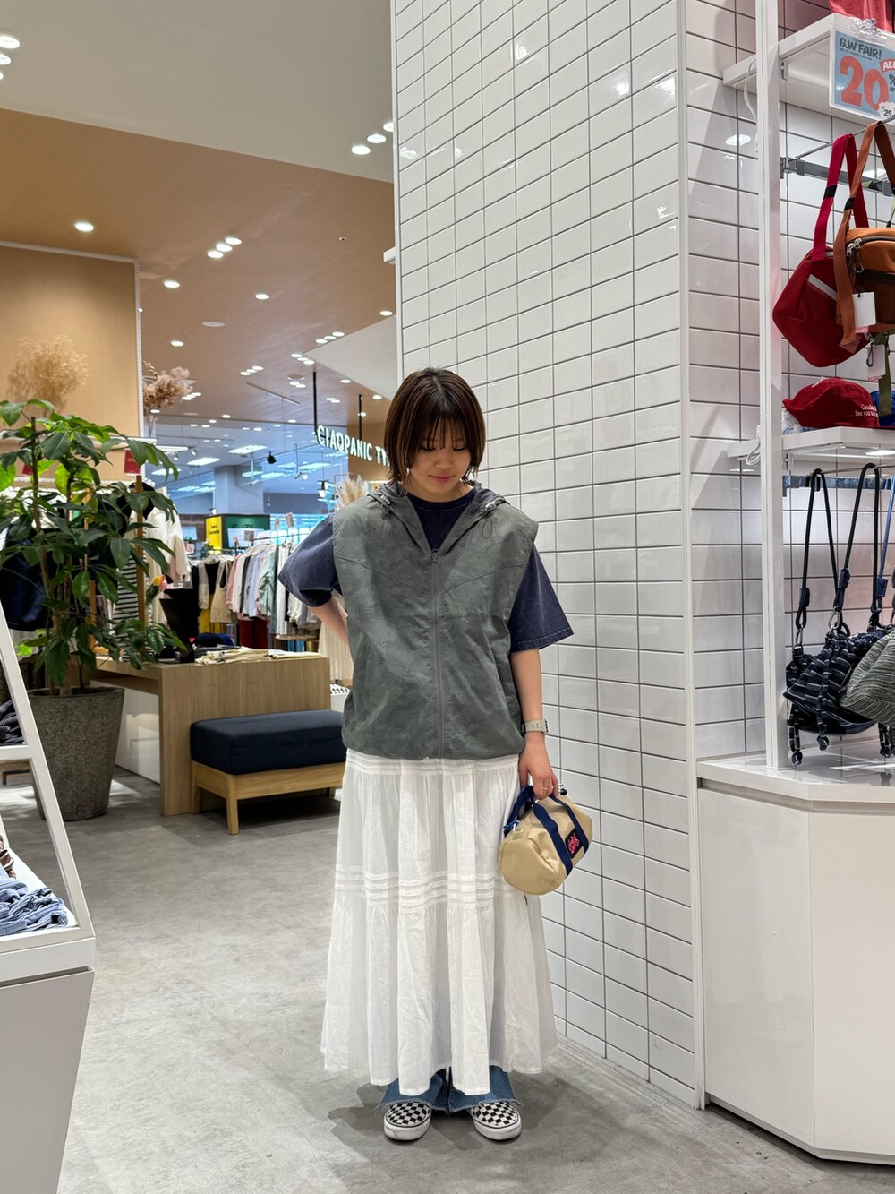 グレー系のベスト、ブルー系のTシャツ/カットソー、ホワイト系のスカートを着用したレディースの春コーディネートの3枚目の写真