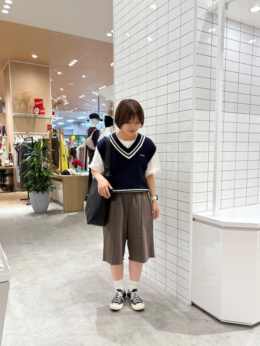 ブラック系のトートバッグ、ブラウン系のスウェットパンツ、ブルー系のベストを着用したレディースの秋コーディネートの2枚目の写真