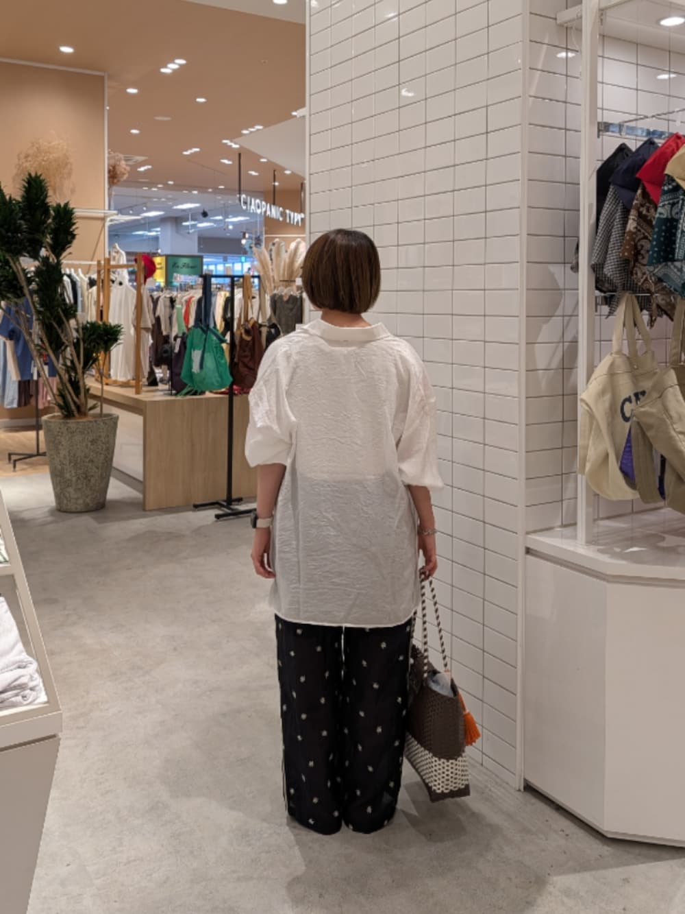 ブラウン系のトートバッグ、ブラック系のその他パンツ、ブラック系のサンダルを着用したレディースの夏コーディネートの4枚目の写真