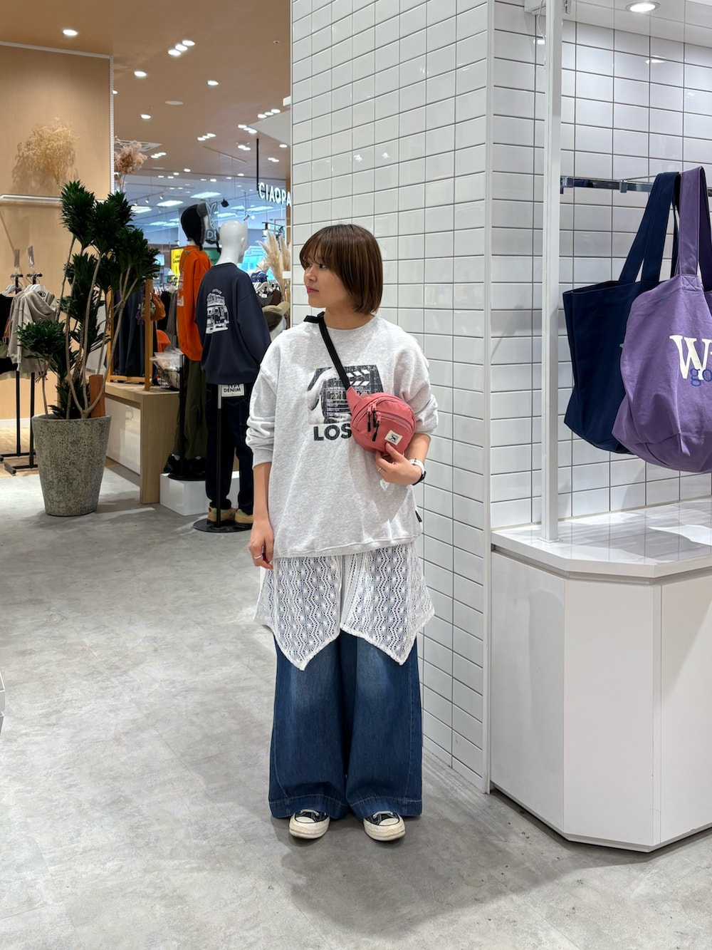 ブルー系のデニムパンツ、ピンク系のボディバッグ/ウエストポーチ、ホワイト系のタンクトップを着用したレディースの秋コーディネートの2枚目の写真