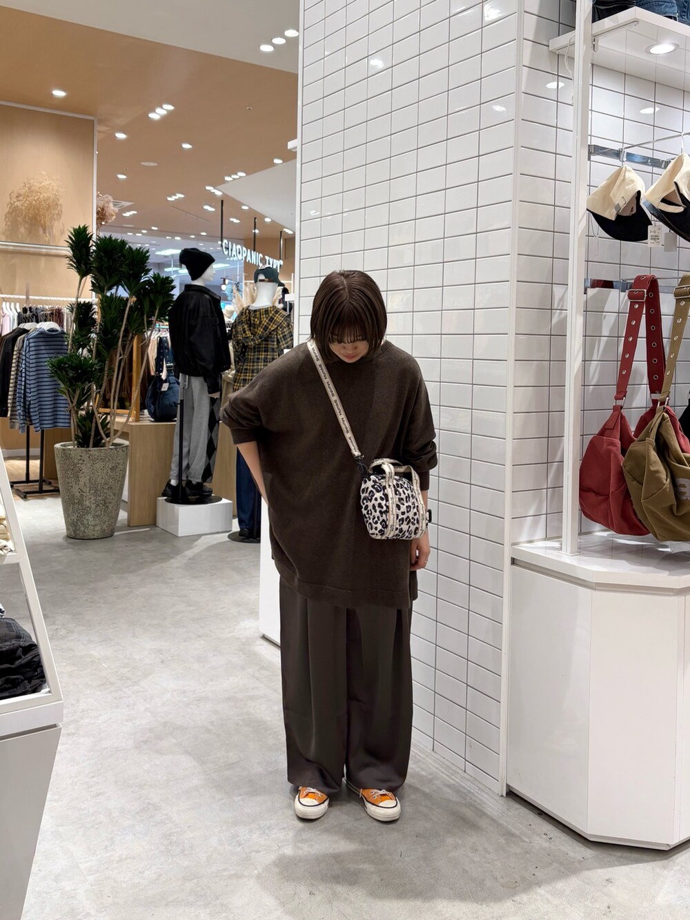 ホワイト系のショルダーバッグ、ブラウン系のニット/セーター、グレー系のその他パンツを着用したレディースの秋コーディネートの2枚目の写真