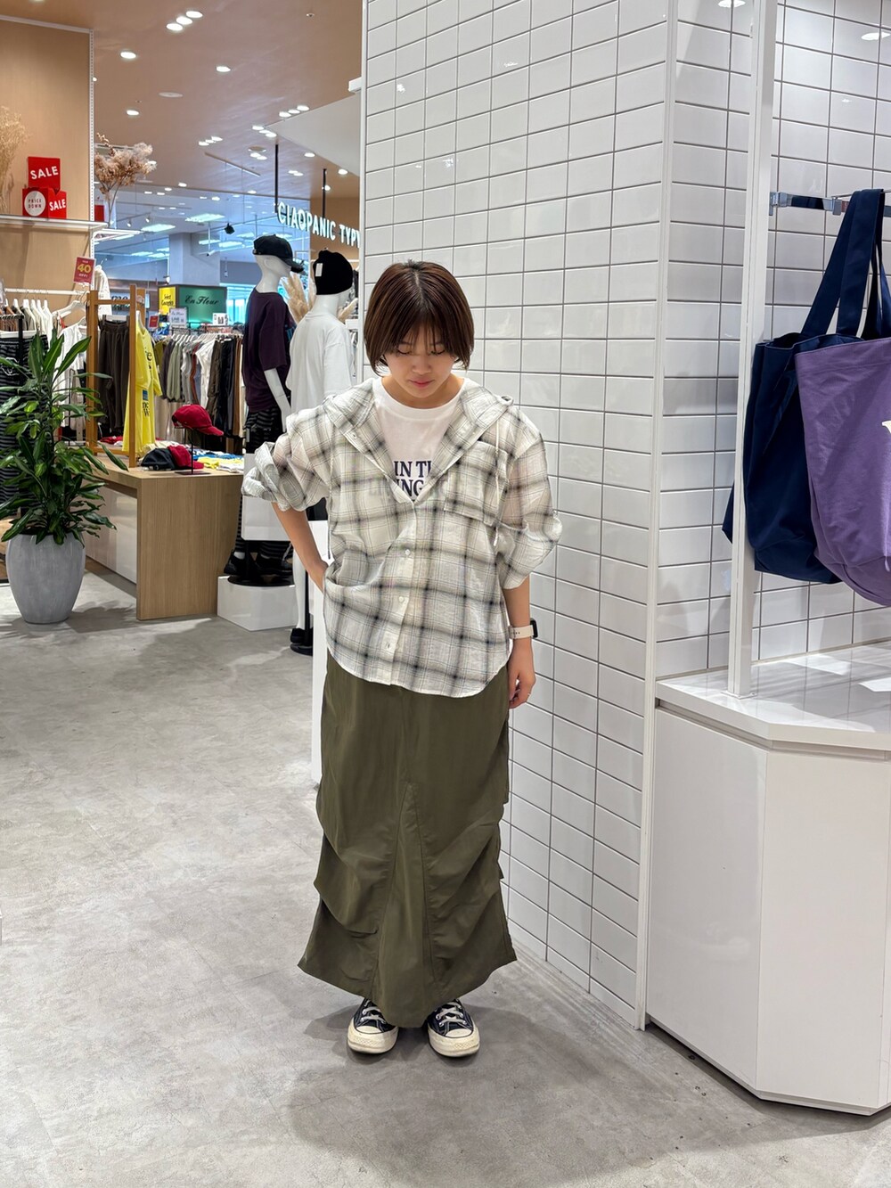 グリーン系のスカート、ホワイト系のシャツ/ブラウス、ホワイト系のTシャツ/カットソーを着用したレディースの秋コーディネートの2枚目の写真