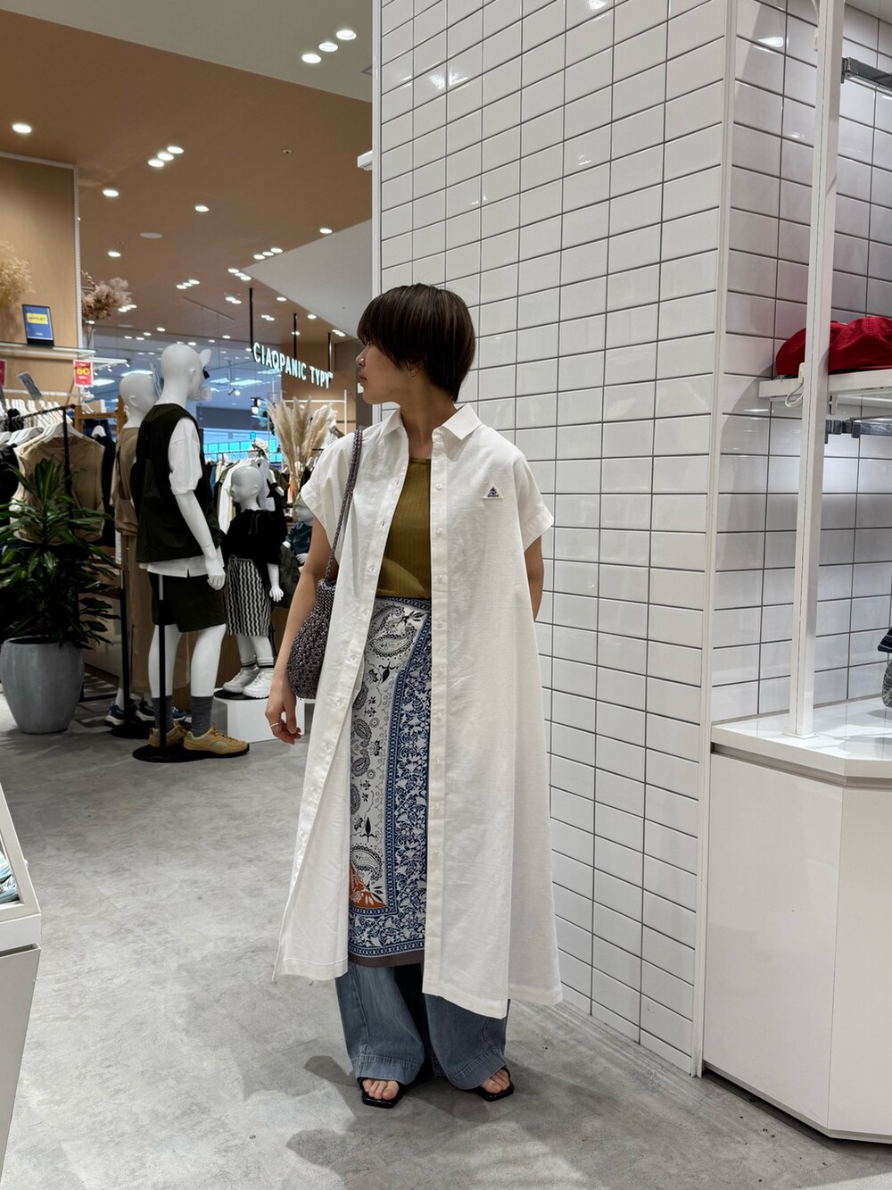 グリーン系のタンクトップ、ホワイト系のワンピース、ブルー系のデニムパンツを着用したレディースの夏コーディネートの3枚目の写真