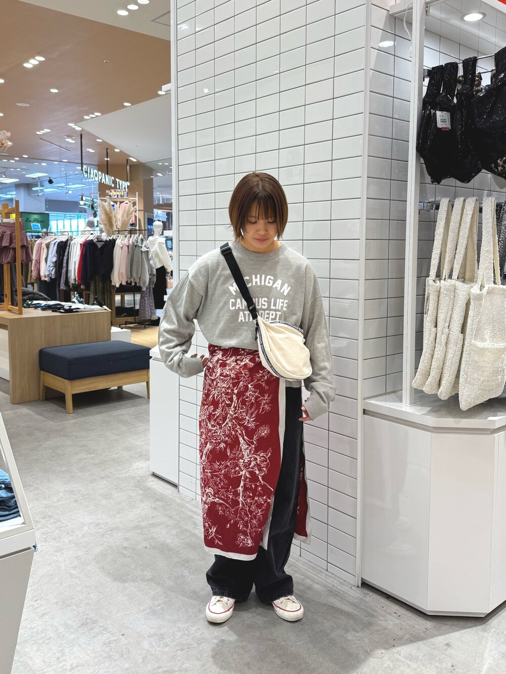 グレー系のニット/セーター、ホワイト系のショルダーバッグ、ブラック系のデニムパンツを着用したレディースの春コーディネートの2枚目の写真