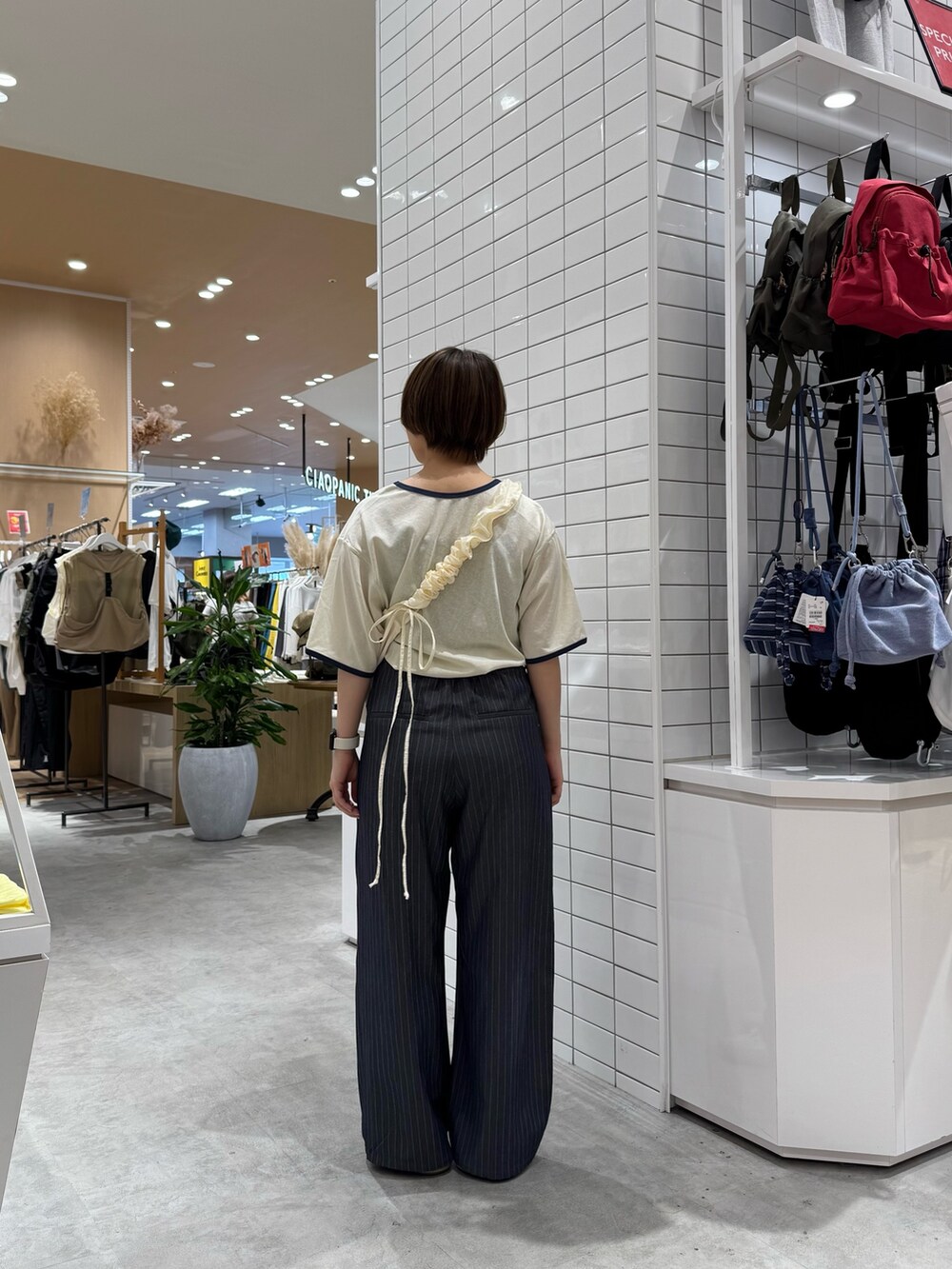 グレー系のスラックス、ホワイト系のトートバッグ、ホワイト系のTシャツ/カットソーを着用したレディースの夏コーディネートの3枚目の写真