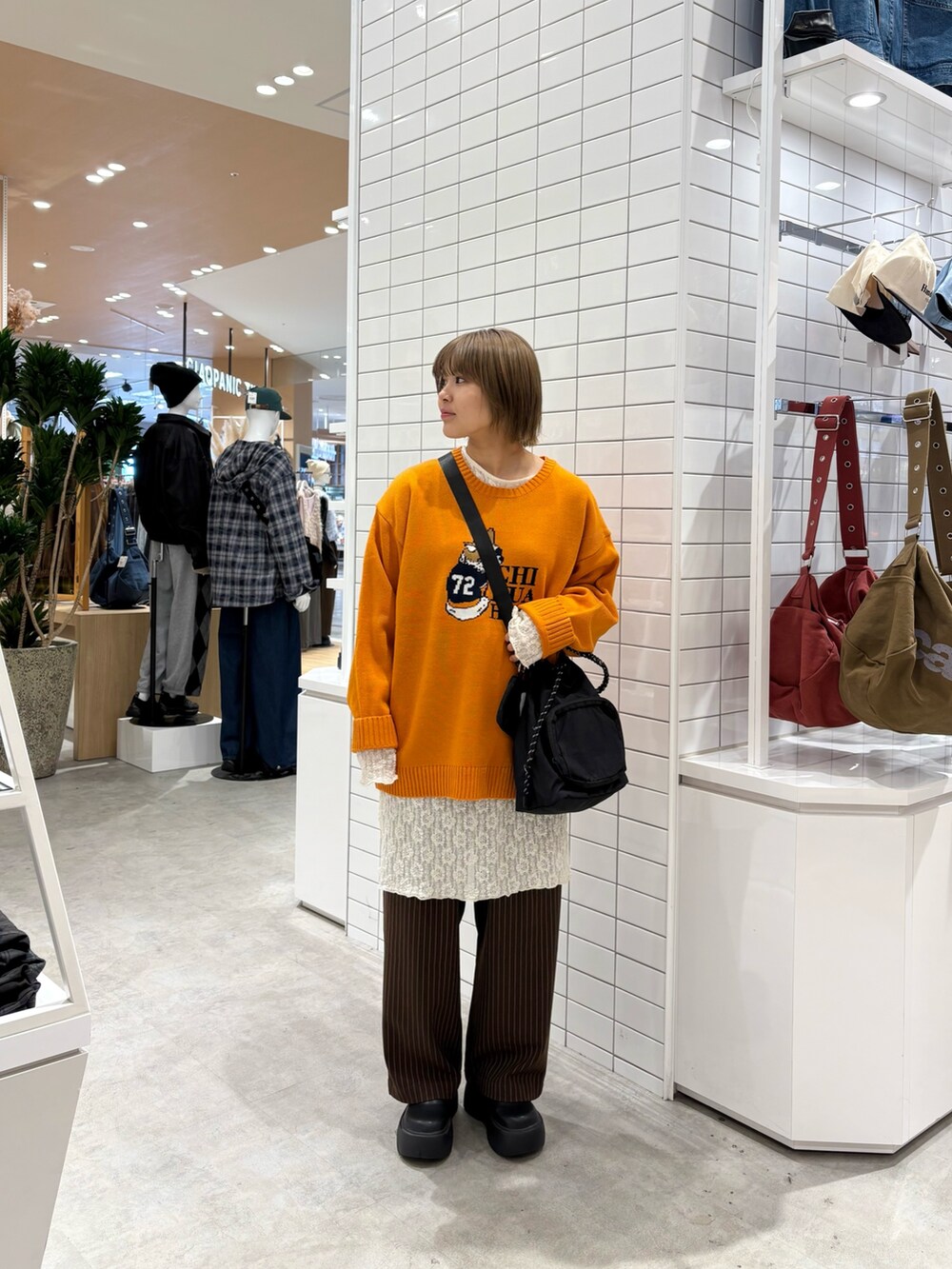 ブラウン系のスラックス、ホワイト系のワンピース、オレンジ系のニット/セーターを着用したレディースの秋コーディネートの3枚目の写真