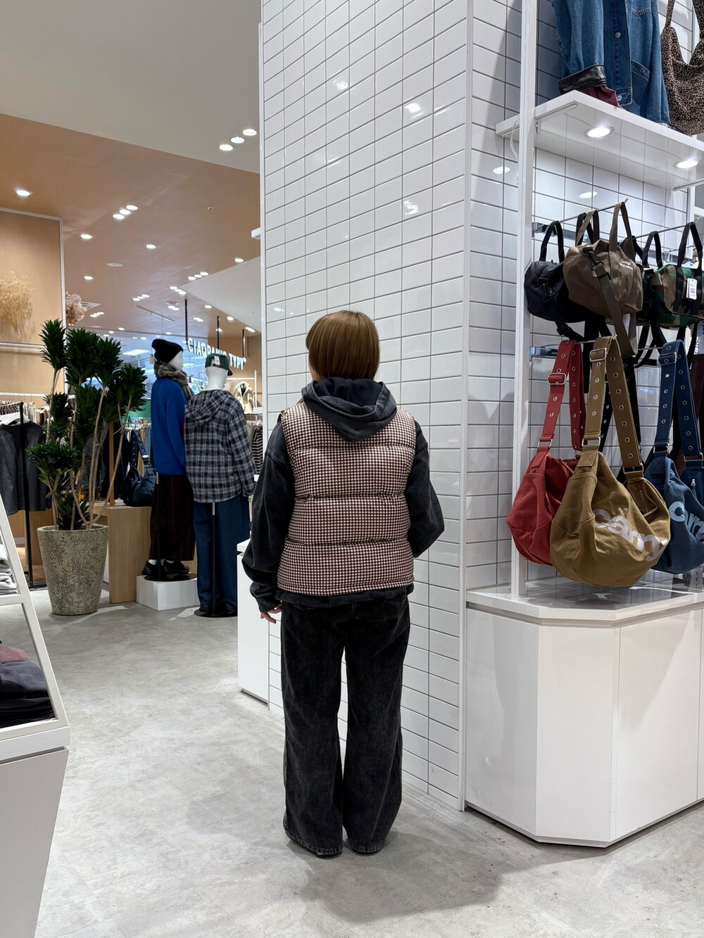 ブラック系のデニムパンツ、ブラック系のパーカー、ブラウン系のベストを着用したレディースの秋コーディネートの4枚目の写真