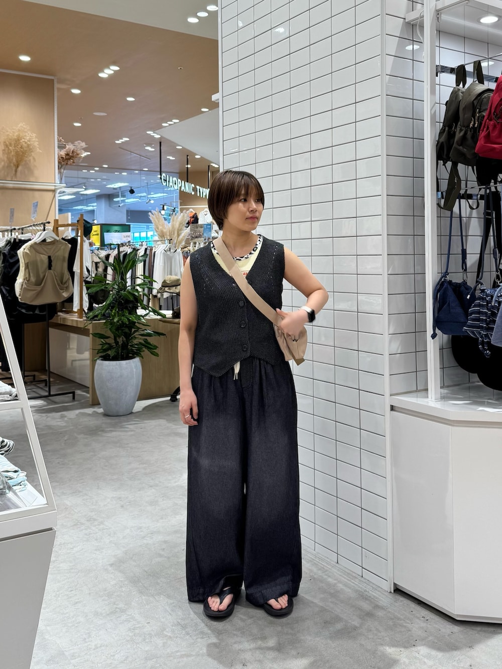 ホワイト系のショルダーバッグ、ブラック系のデニムパンツ、グレー系のベストを着用したレディースの夏コーディネートの3枚目の写真