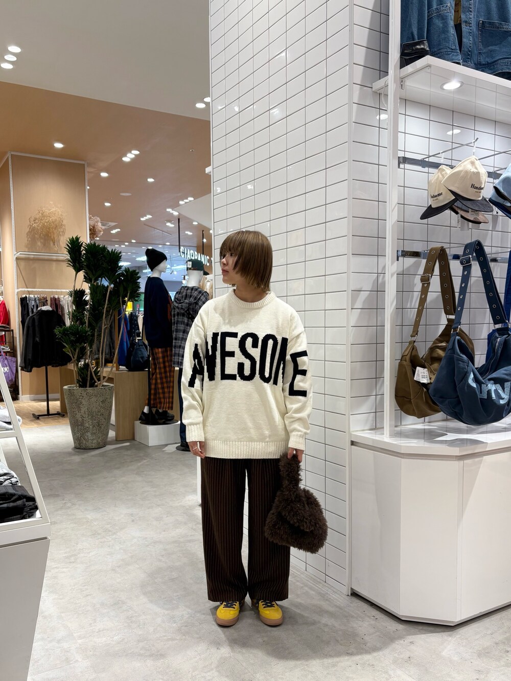 ホワイト系のニット/セーター、ブラウン系のスラックス、ブラウン系のトートバッグを着用したレディースの秋コーディネートの2枚目の写真