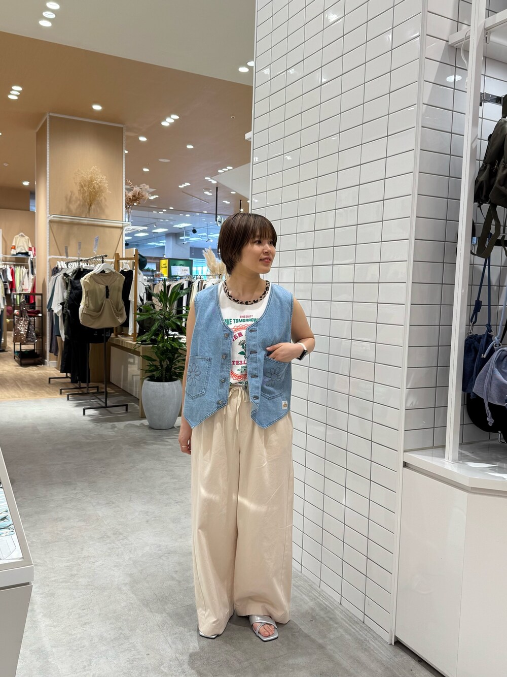 ホワイト系のデニムパンツ、シルバー系のサンダル、ホワイト系のタンクトップを着用したレディースの夏コーディネートの2枚目の写真