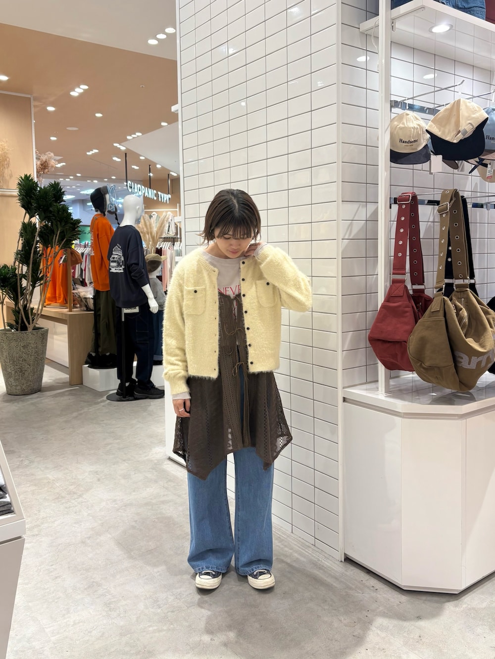 ブラウン系のタンクトップ、ブルー系のデニムパンツ、イエロー系のカーディガン/ボレロを着用したレディースの秋コーディネートの2枚目の写真