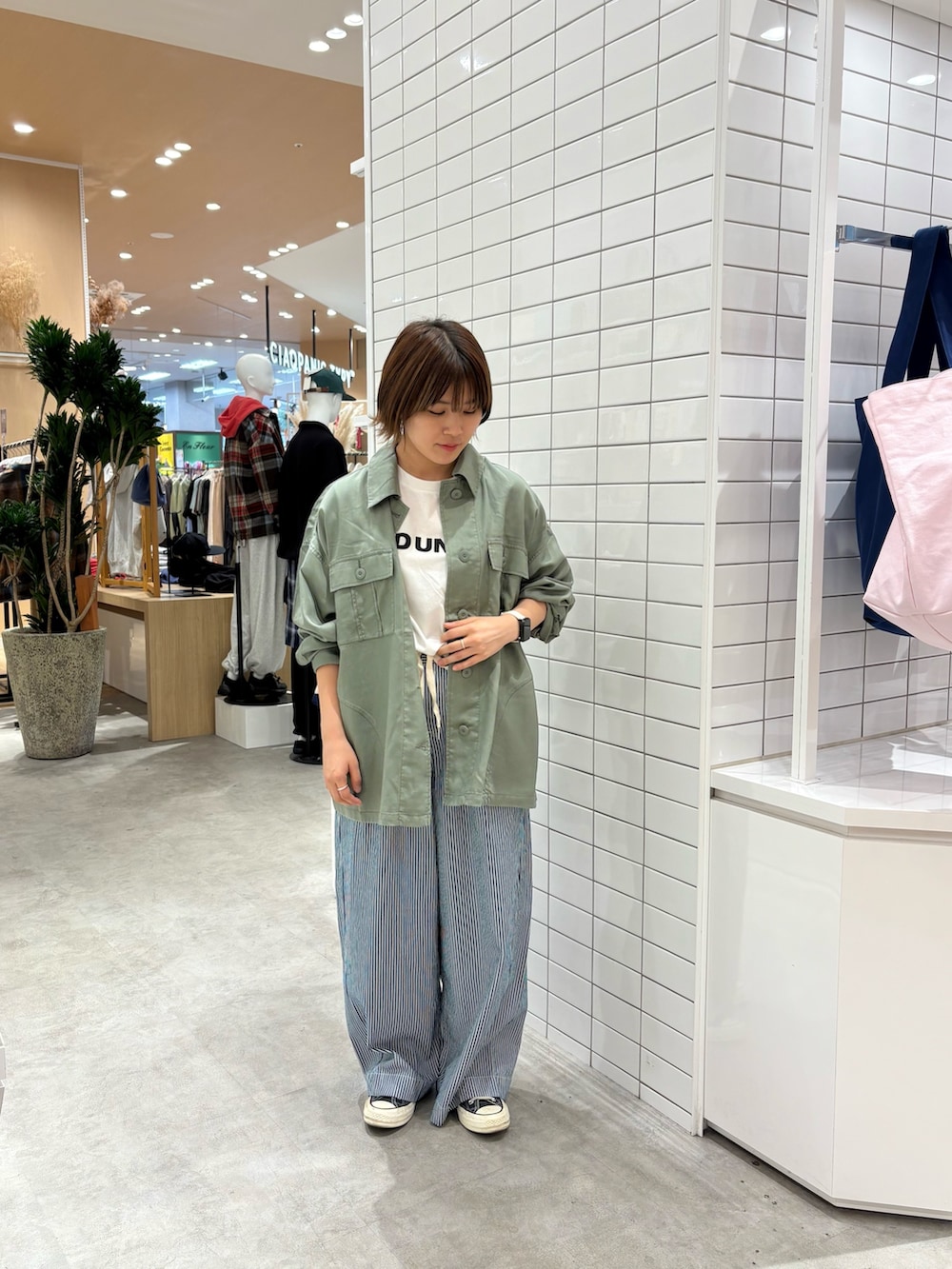 ブルー系のデニムパンツ、ホワイト系のTシャツ/カットソー、グリーン系のシャツ/ブラウスを着用したレディースの秋コーディネートの2枚目の写真