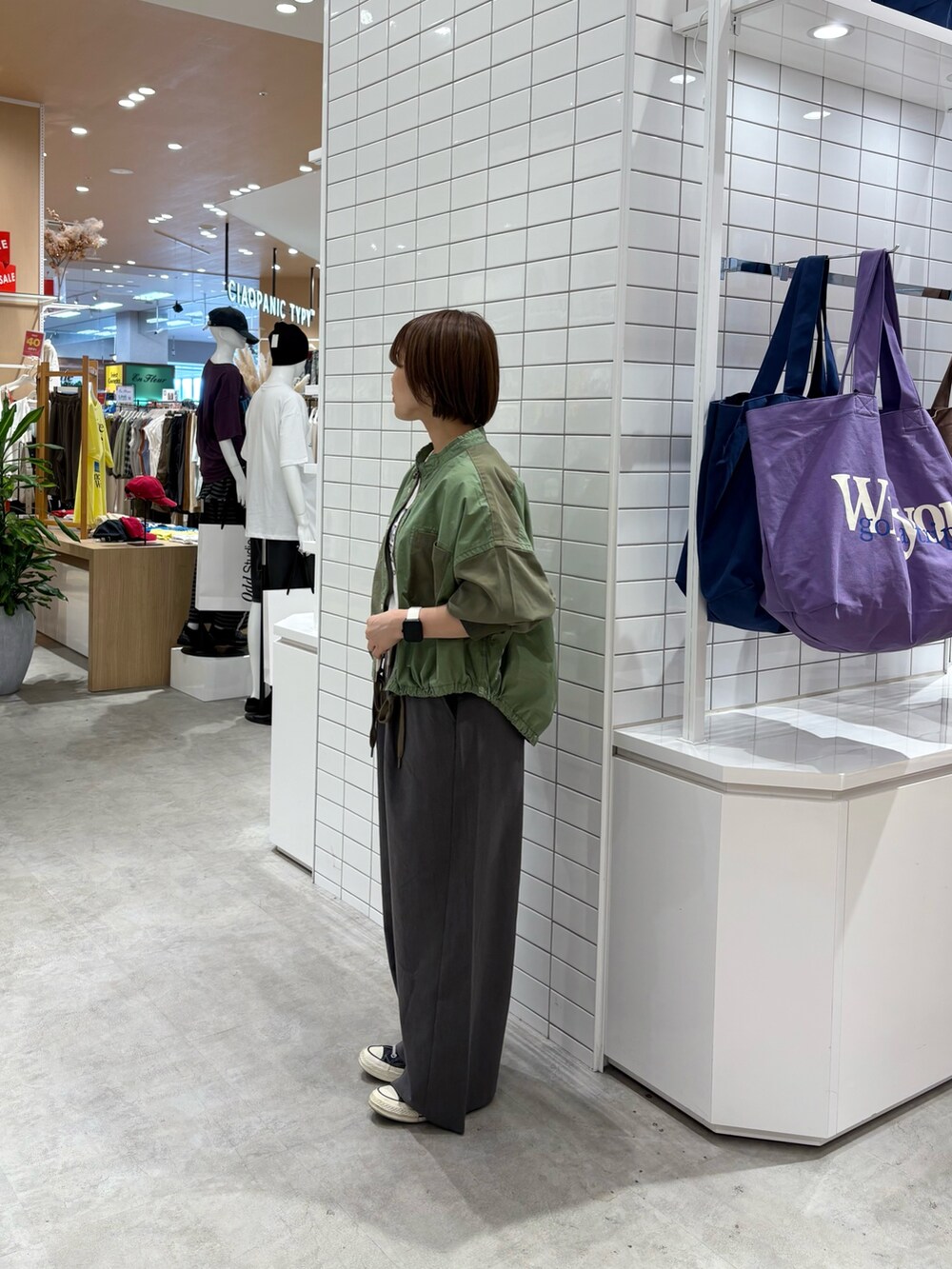 グレー系のデニムパンツ、ホワイト系のTシャツ/カットソー、グリーン系のブルゾンを着用したレディースの秋コーディネートの4枚目の写真