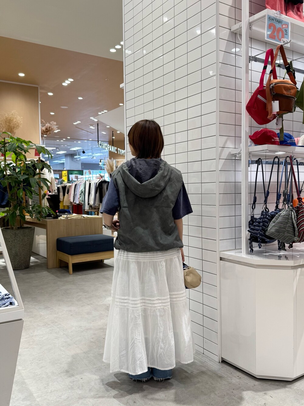 グレー系のベスト、ブルー系のTシャツ/カットソー、ホワイト系のスカートを着用したレディースの春コーディネートの4枚目の写真