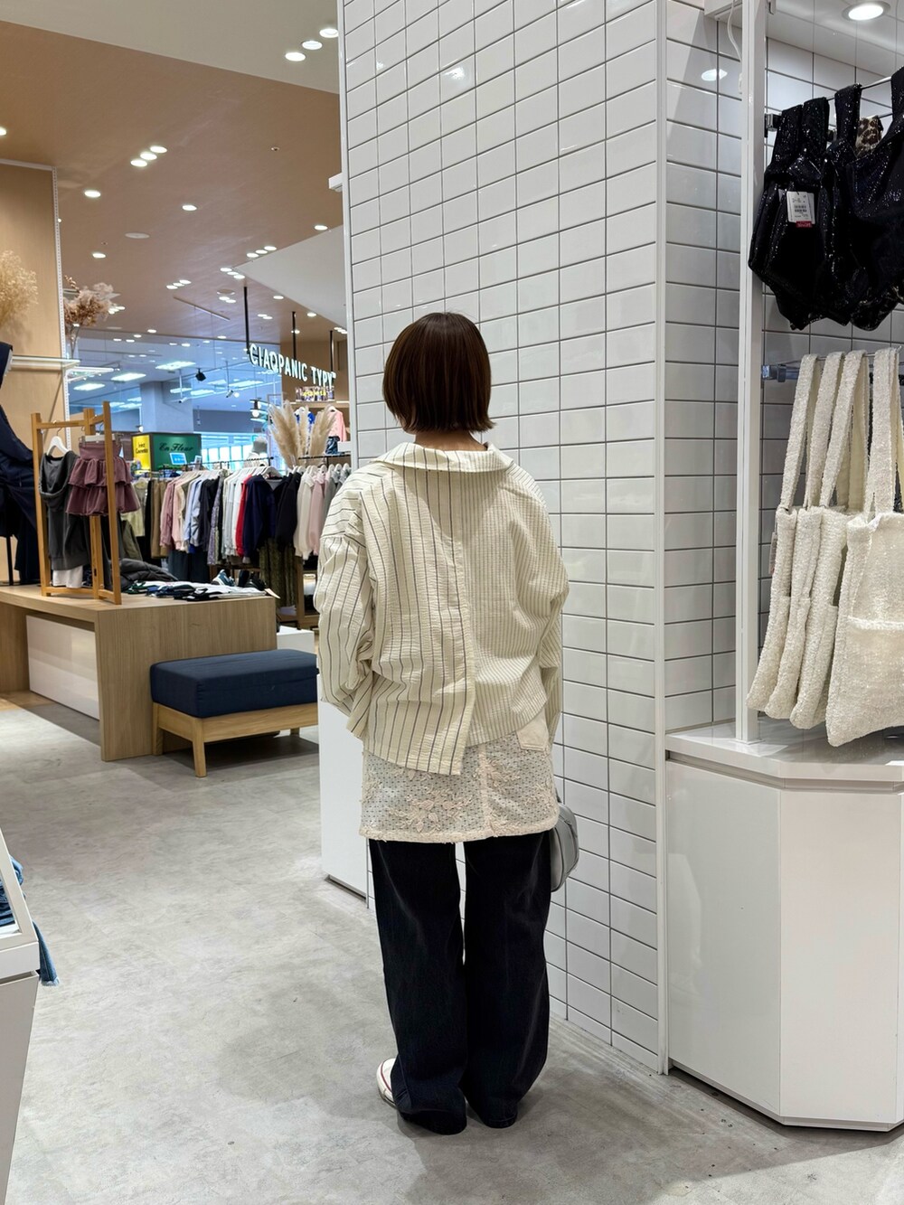 ホワイト系のTシャツ/カットソー、ホワイト系のスカート、ブラック系のデニムパンツを着用したレディースの春コーディネートの4枚目の写真