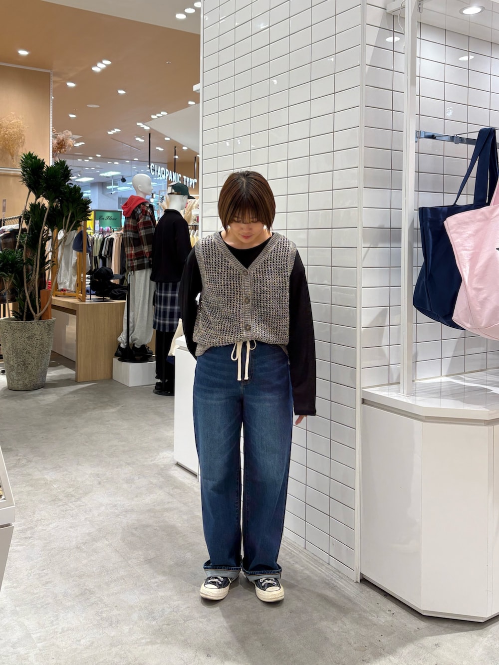 ブルー系のデニムパンツ、グレー系のニット/セーター、ブラック系のTシャツ/カットソーを着用したレディースの秋コーディネートの2枚目の写真