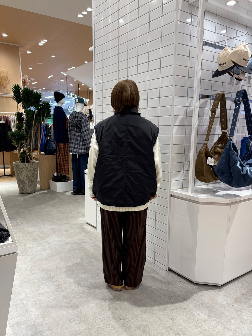 ホワイト系のニット/セーター、ブラウン系のスラックス、ブラック系のブルゾンを着用したレディースの秋コーディネートの5枚目の写真