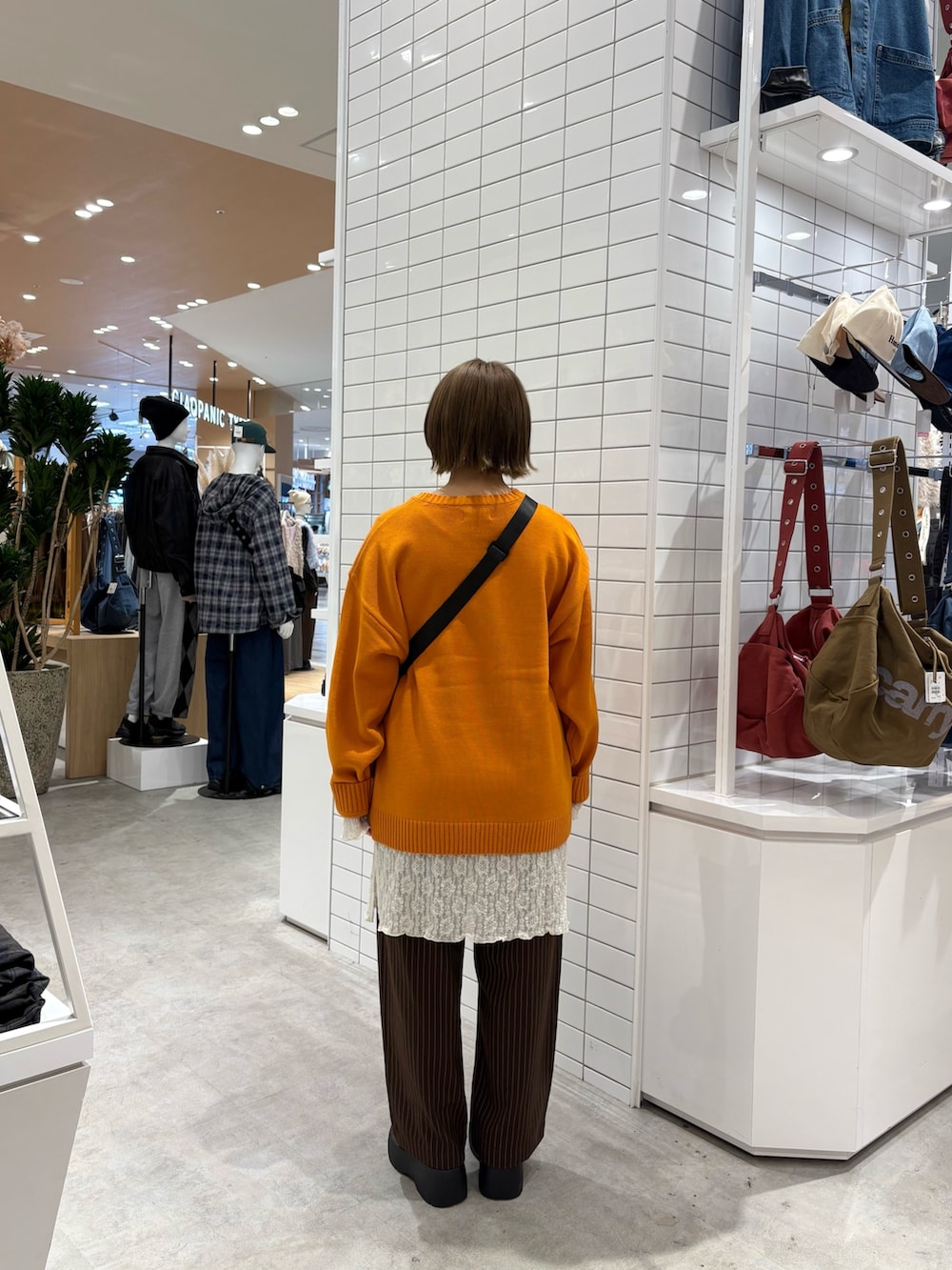 ブラウン系のスラックス、ホワイト系のワンピース、オレンジ系のニット/セーターを着用したレディースの秋コーディネートの4枚目の写真