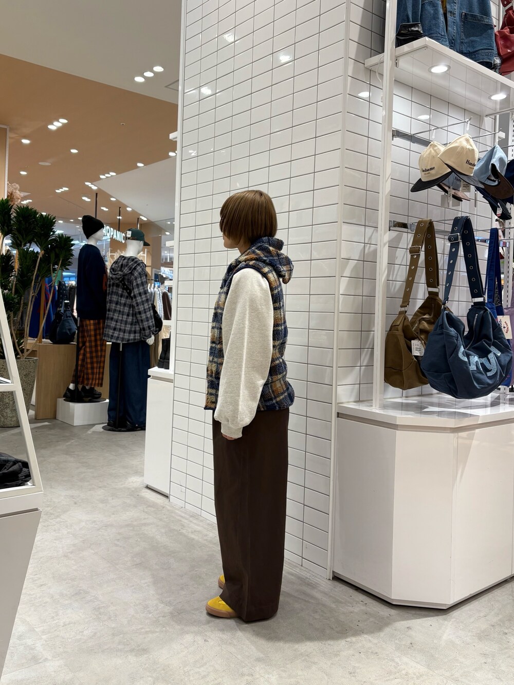 ブラウン系のデニムパンツ、ホワイト系のスウェット、オレンジ系のベストを着用したレディースの秋コーディネートの4枚目の写真