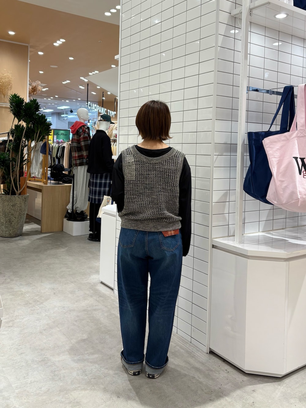 ブルー系のデニムパンツ、グレー系のニット/セーター、ブラック系のTシャツ/カットソーを着用したレディースの秋コーディネートの4枚目の写真