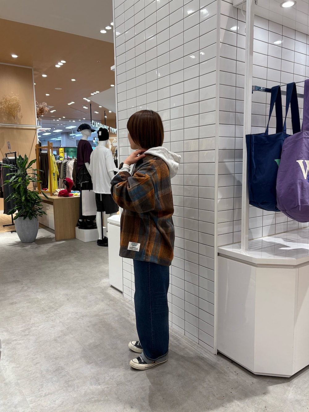 オレンジ系のシャツ/ブラウス、グレー系のパーカー、ブルー系のデニムパンツを着用したレディースの秋コーディネートの3枚目の写真