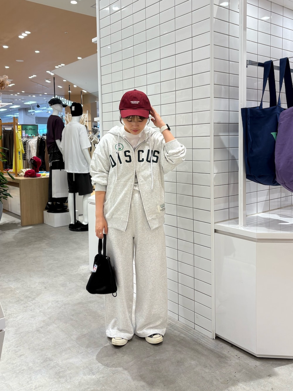 グレー系のパーカー、グレー系のスウェットパンツ、ブラック系のハンドバッグを着用したレディースの秋コーディネートの2枚目の写真