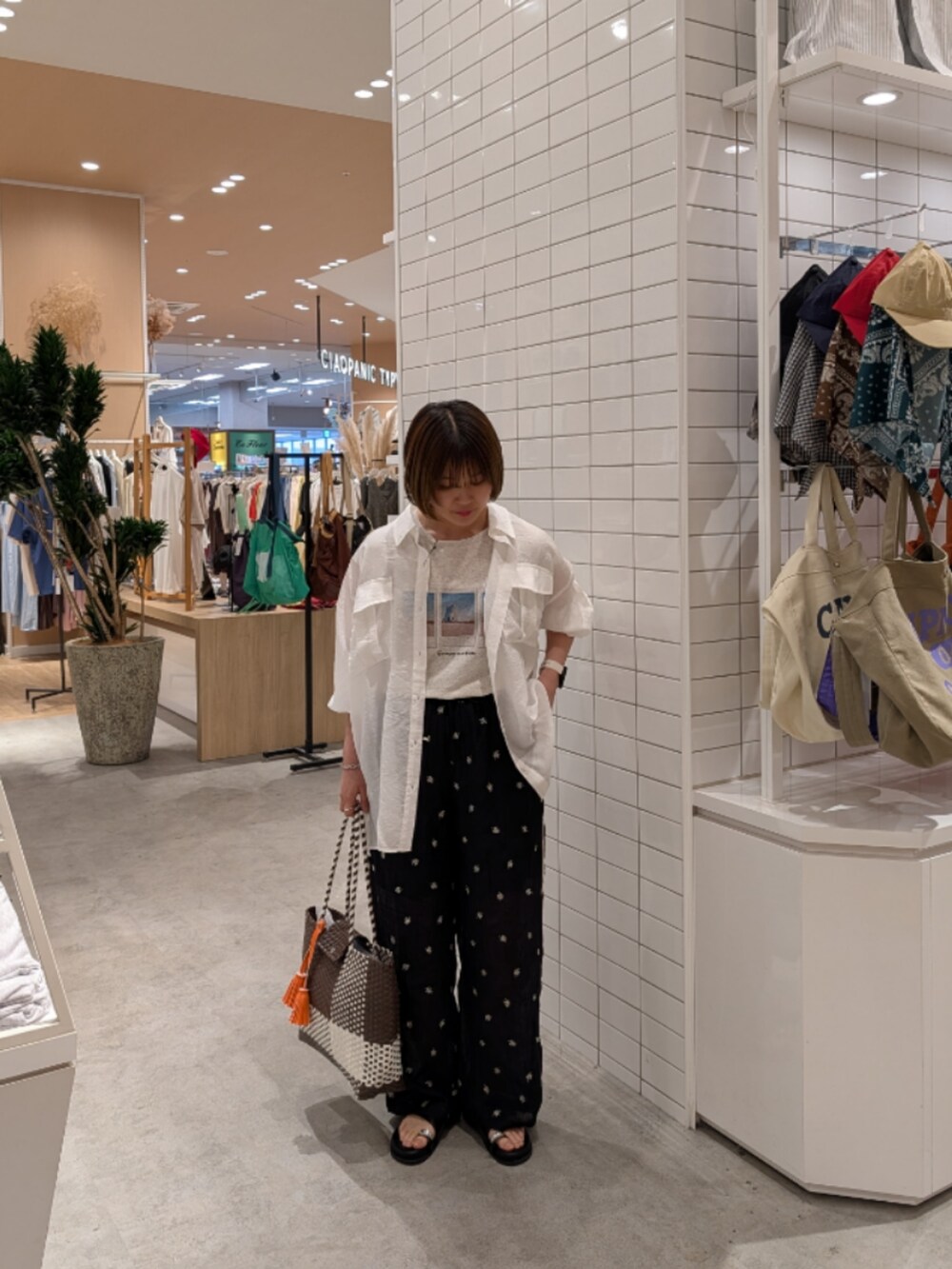 ブラウン系のトートバッグ、ブラック系のその他パンツ、ブラック系のサンダルを着用したレディースの夏コーディネートの2枚目の写真