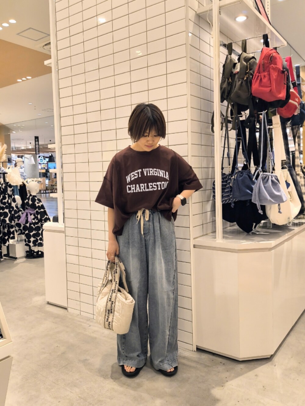 ブルー系のデニムパンツ、ホワイト系のトートバッグ、ブラウン系のTシャツ/カットソーを着用したレディースの夏コーディネートの3枚目の写真