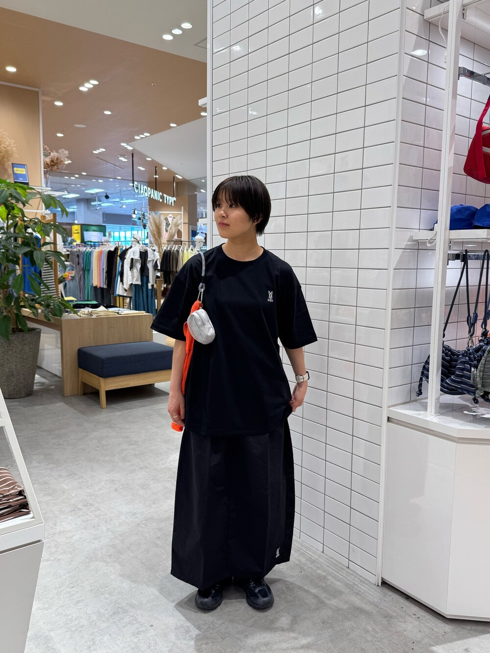 ブラック系のTシャツ/カットソー、ブラック系のスカート、オレンジ系のトートバッグを着用したレディースの春コーディネートの3枚目の写真