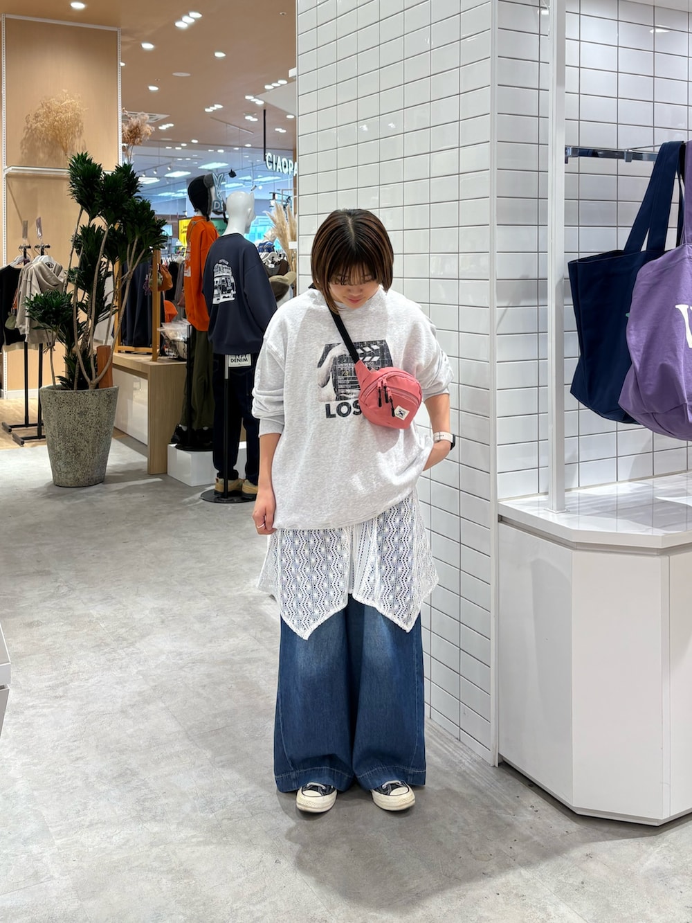 ブルー系のデニムパンツ、ピンク系のボディバッグ/ウエストポーチ、ホワイト系のタンクトップを着用したレディースの秋コーディネートの3枚目の写真