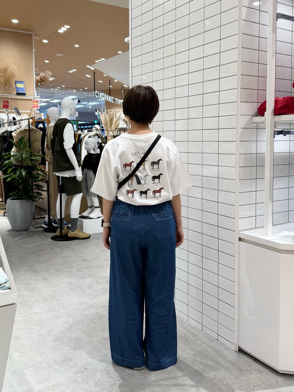 ブラック系のトートバッグ、ホワイト系のTシャツ/カットソー、ブルー系のデニムパンツを着用したレディースの春コーディネートの4枚目の写真