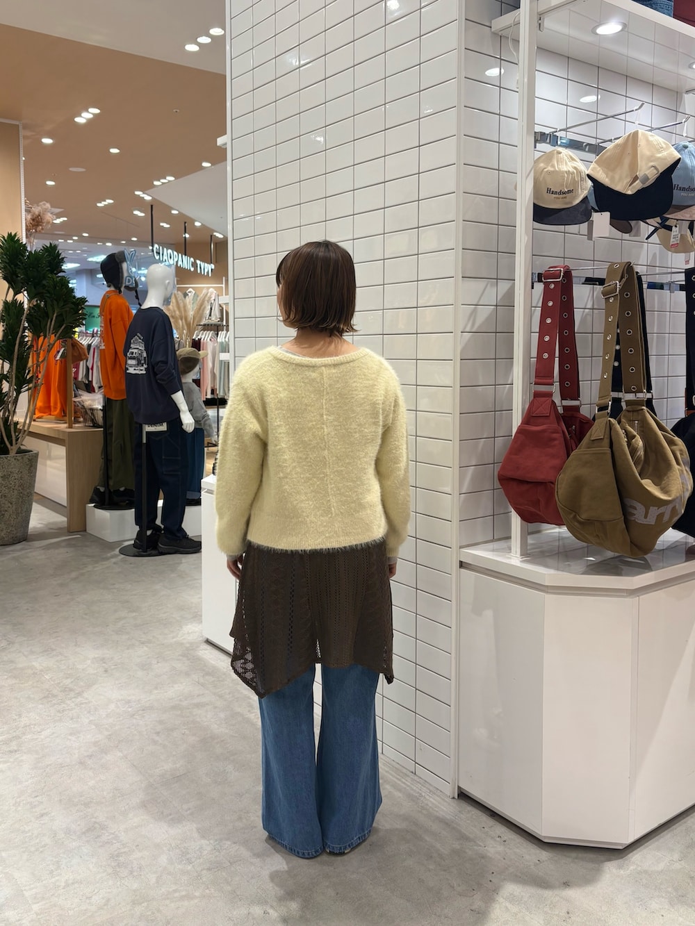 ブラウン系のタンクトップ、ブルー系のデニムパンツ、イエロー系のカーディガン/ボレロを着用したレディースの秋コーディネートの3枚目の写真