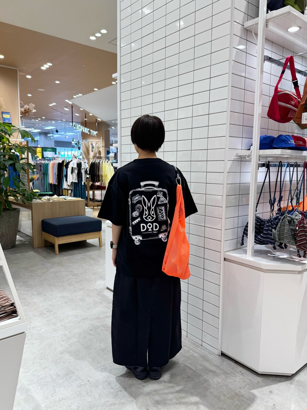 ブラック系のTシャツ/カットソー、ブラック系のスカート、オレンジ系のトートバッグを着用したレディースの春コーディネートの5枚目の写真