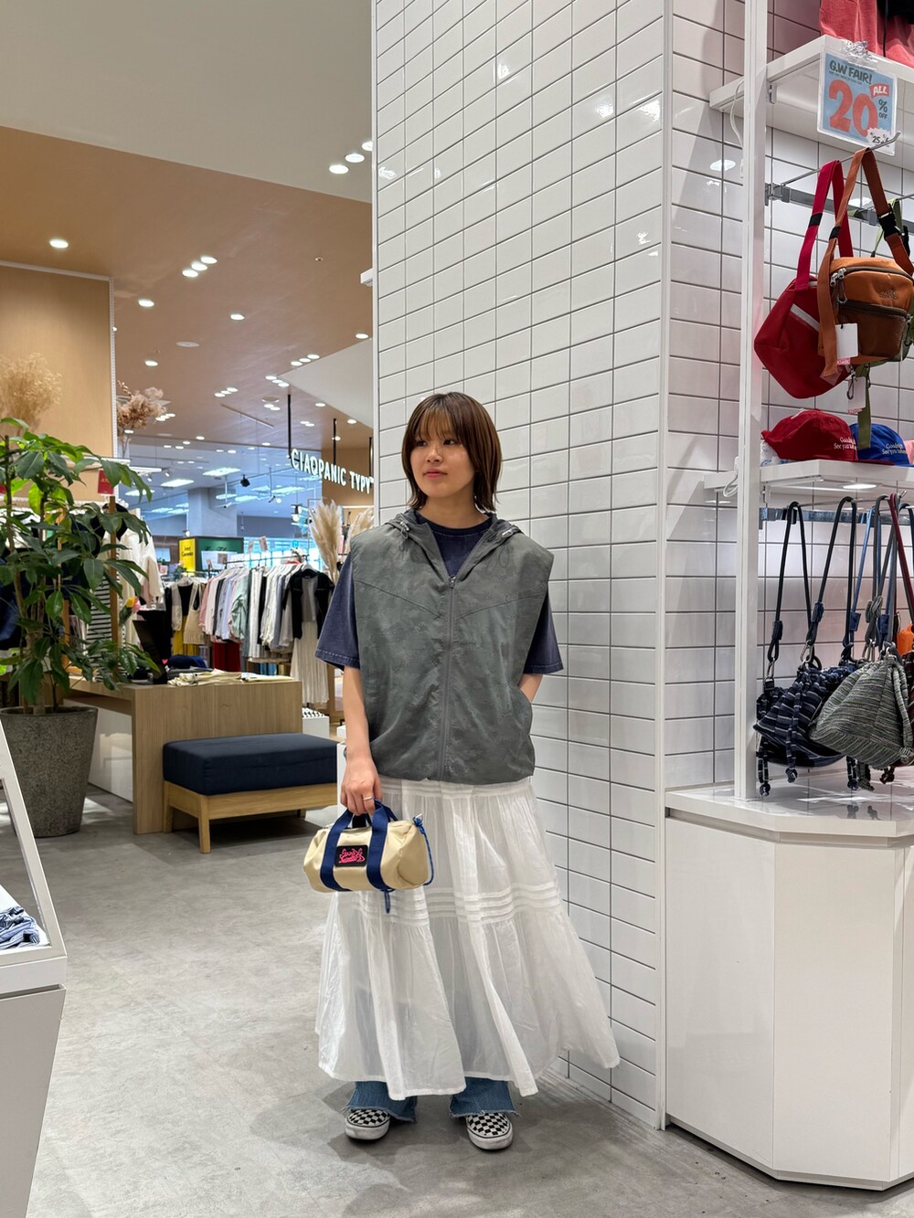 グレー系のベスト、ブルー系のTシャツ/カットソー、ホワイト系のスカートを着用したレディースの春コーディネートの2枚目の写真