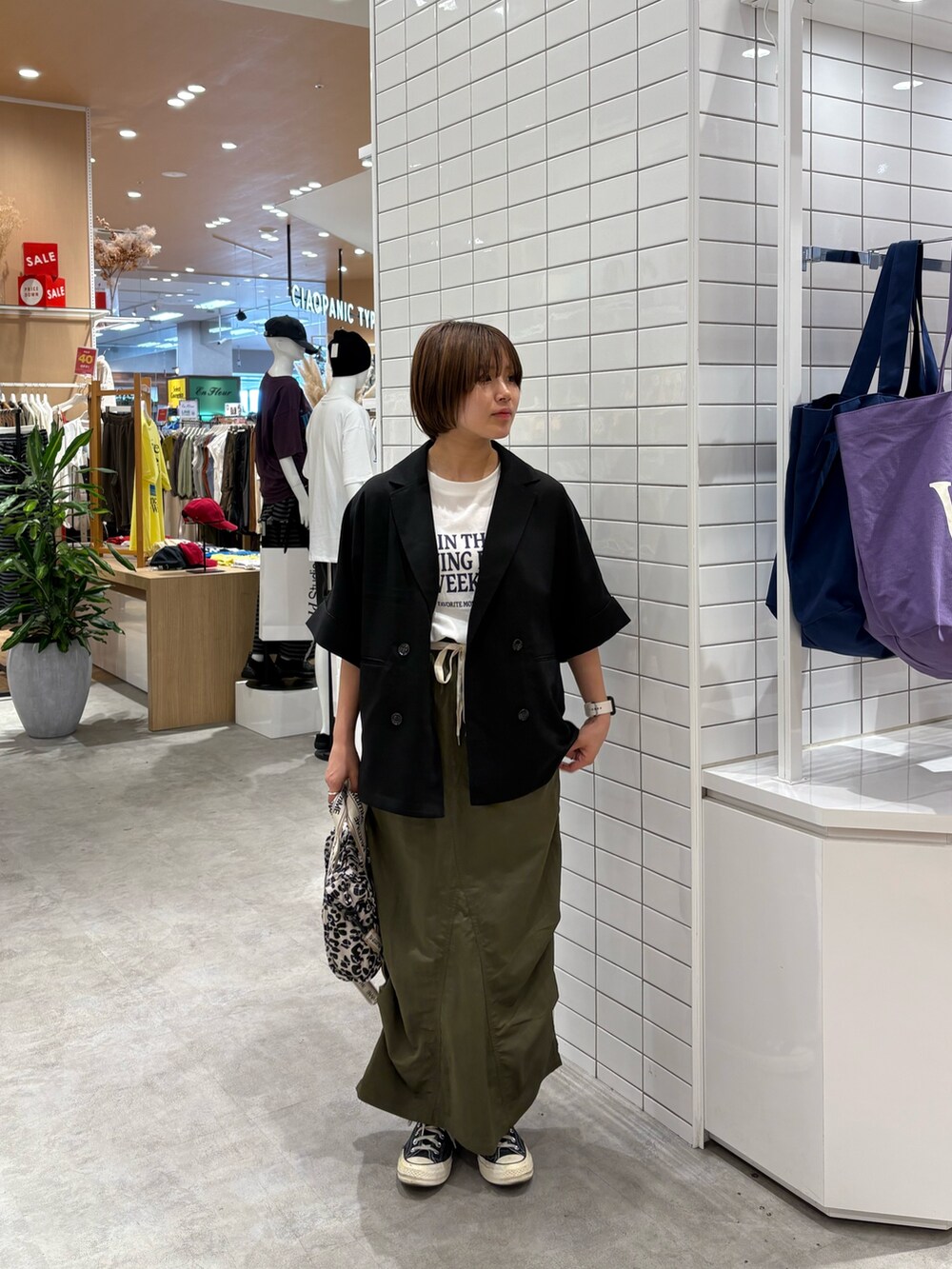 ホワイト系のTシャツ/カットソー、ブラック系のテーラードジャケット、グリーン系のスカートを着用したレディースの秋コーディネートの3枚目の写真