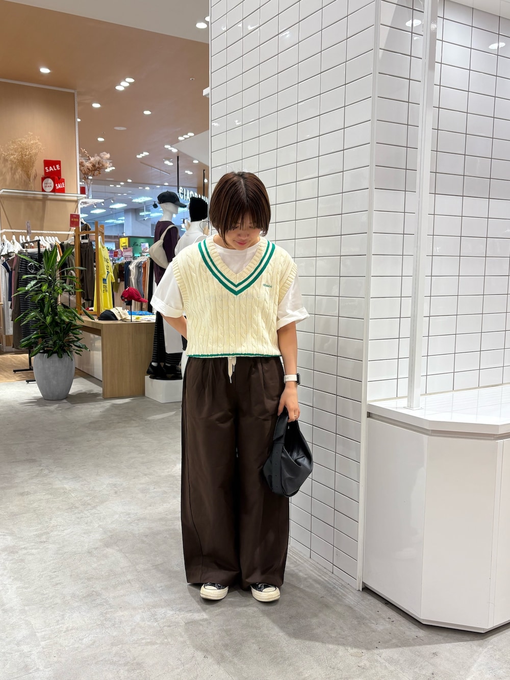 ホワイト系のTシャツ/カットソー、ホワイト系のベスト、ブラウン系のデニムパンツを着用したレディースの秋コーディネートの2枚目の写真