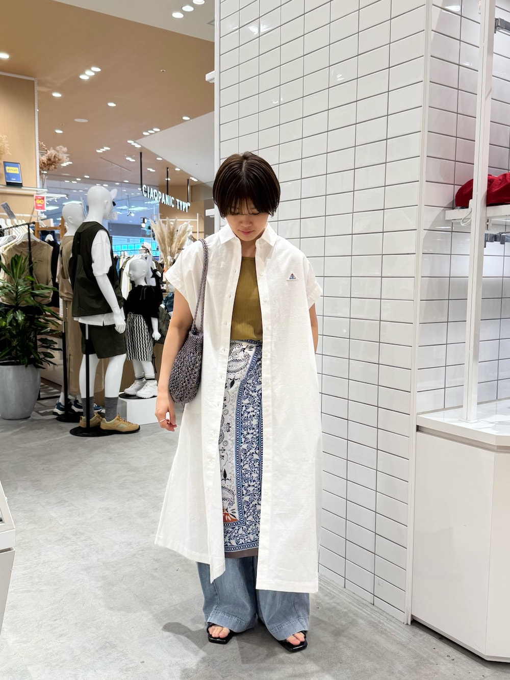 グリーン系のタンクトップ、ホワイト系のワンピース、ブルー系のデニムパンツを着用したレディースの夏コーディネートの2枚目の写真